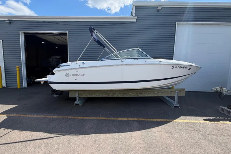 Slide: The Image of 2014 Cobalt 210 boat on trailer outside a garage under a blue sky. - 2