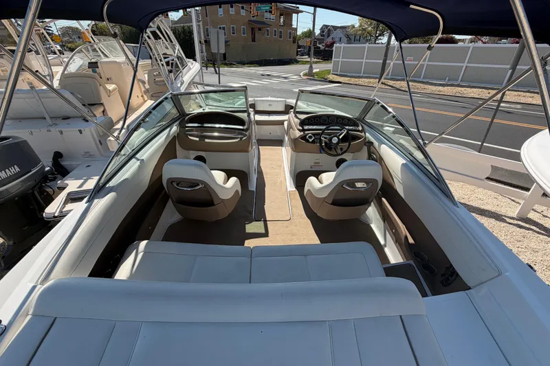 Slide: The Image of 2014 Cobalt 210 boat interior with seating and steering wheel, parked outdoors. - 24