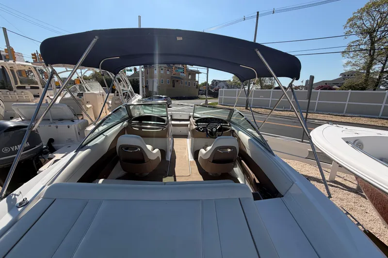 Slide: The Image of 2014 Cobalt 210 boat with canopy, dual seats, and steering wheel, parked outdoors. - 25