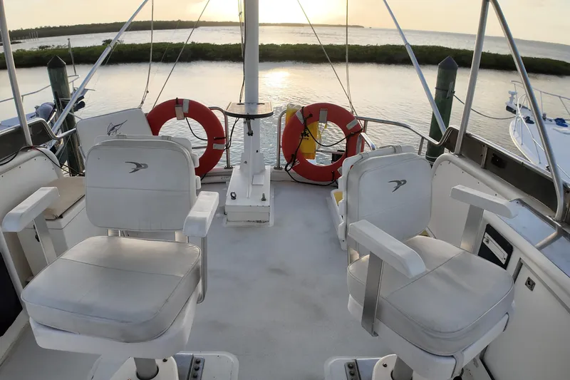 Slide: The Image of Deck view of 1999 Anderson Downeast Aluminum Fast Trawler at sunset, featuring two chairs and life rings. - 25