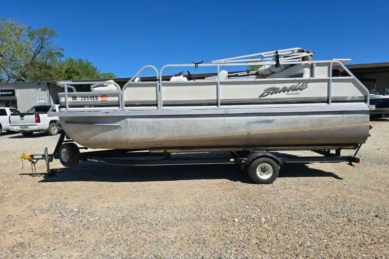 Slide: The Image of 2004 Bandit Pontoon boat on trailer, parked outdoors under clear blue sky. - 3