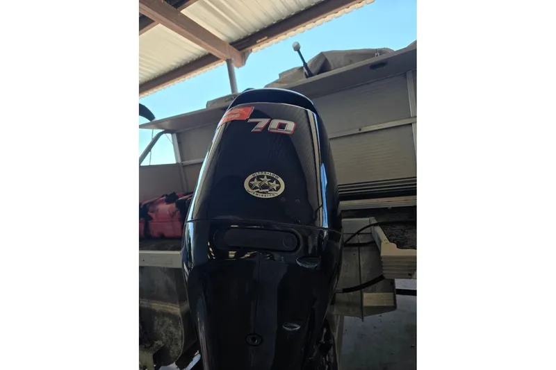 Slide: The Image of Outboard motor on a 2004 Bandit Pontoon boat under a metal roof. - 9