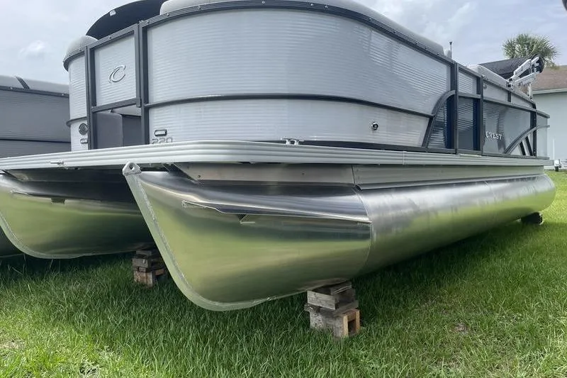 The Image of 2024 Crest Classic 220 pontoon boat on grass, showcasing sleek aluminum pontoons. - 0