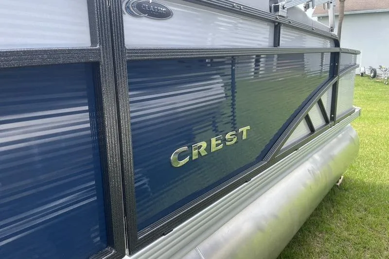 Slide: The Image of 2024 Crest Classic 220 pontoon boat with sleek blue and silver design. - 1