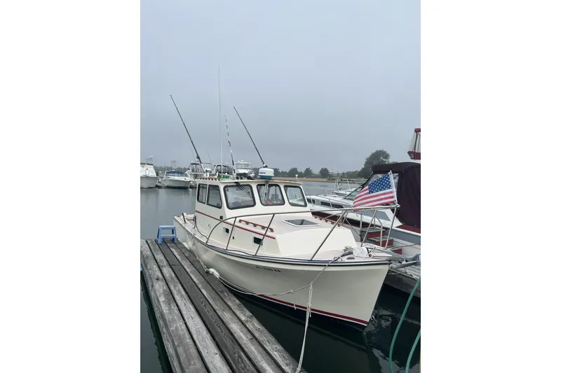 Slide: The Image of 1998 General Marine Custom Downeast boat docked with American flag, overcast sky. - 4