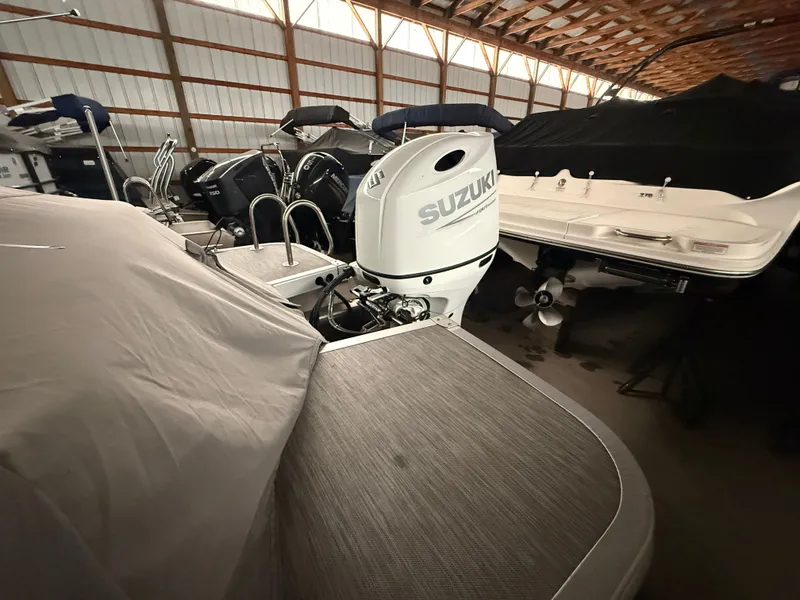 Slide: The Image of 2021 Bennington SSBXSD boat with Suzuki outboard motor in storage facility. - 2