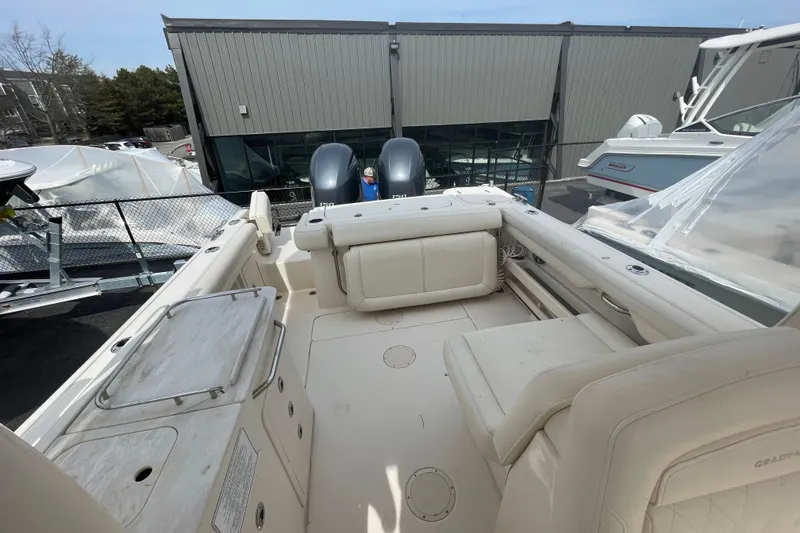 Slide: The Image of 2017 Grady-White Freedom 275 boat interior with seating and dual engines, docked outdoors. - 12