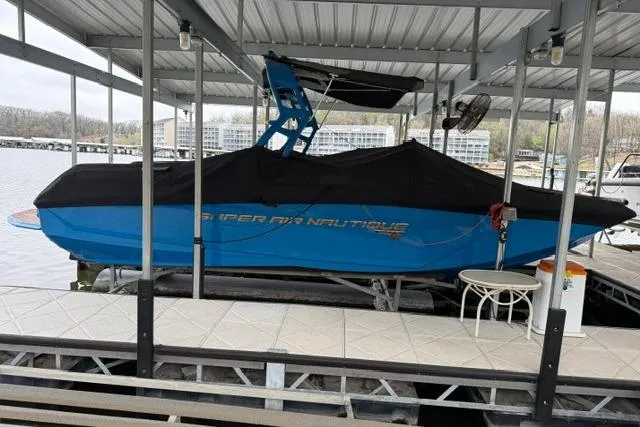 Slide: The Image of 2020 Nautique Super Air Nautique G25 boat docked under a covered marina. - 29