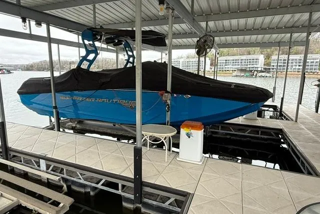 Slide: The Image of 2020 Nautique Super Air Nautique G25 boat docked under a covered marina. - 33