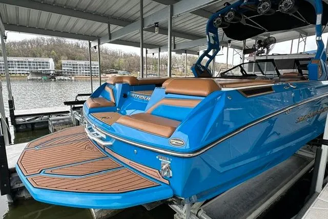 Slide: The Image of 2020 Nautique Super Air Nautique G25 boat docked, featuring blue exterior and brown seating. - 35
