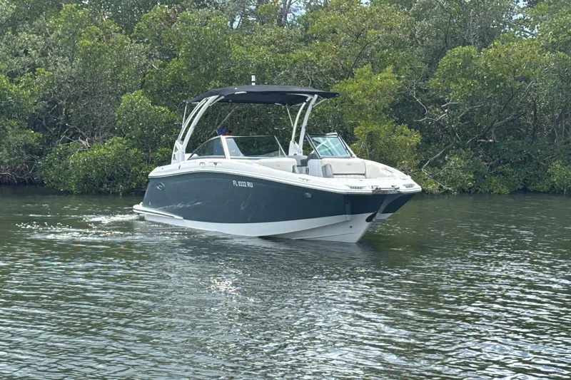 Slide: The Image of 2019 Cobalt 23SC boat cruising on a calm river with lush greenery. - 3
