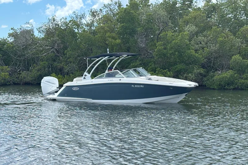 Slide: The Image of 2019 Cobalt 23SC boat cruising on a calm river with lush greenery. - 2