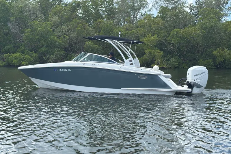 Slide: The Image of 2019 Cobalt 23SC boat on calm water, surrounded by lush greenery. - 6