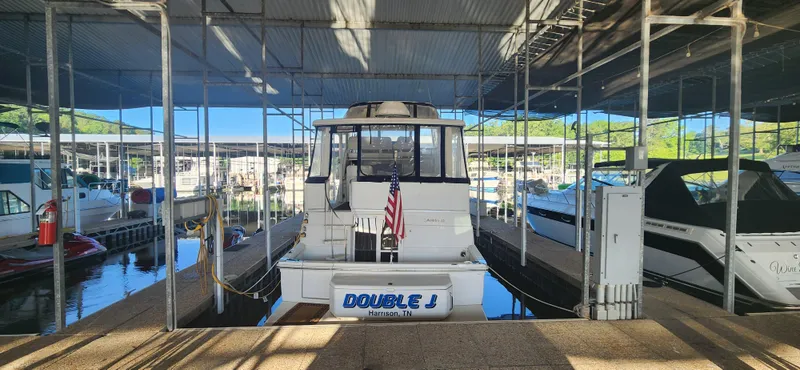 Slide: The Image of 1996 Carver 400 Cockpit Motor Yacht docked in marina, rear view with American flag. - 4
