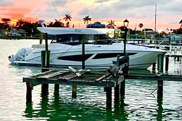 Slide: The Image of 2021 Regal 42 XO yacht docked at sunset with palm trees in the background. - 10
