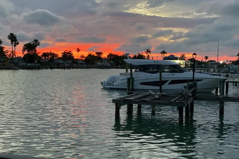 Slide: The Image of 2021 Regal 42 XO yacht docked at sunset with palm trees and vibrant sky. - 11
