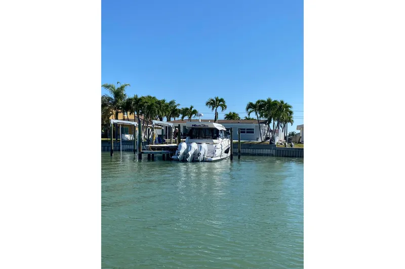 Slide: The Image of 2021 Regal 42 XO yacht docked by palm trees under clear blue sky. - 12