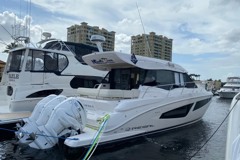 Slide: The Image of 2021 Regal 42 XO yacht docked at marina with modern buildings in background. - 14