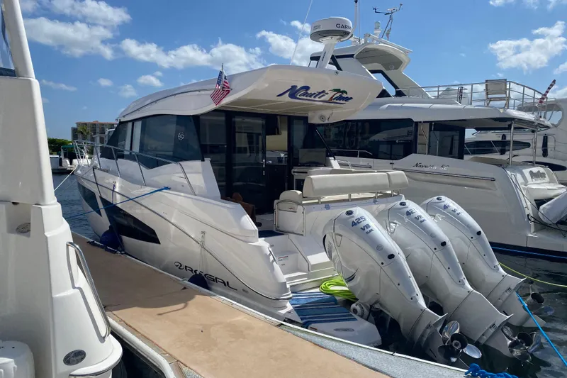 Slide: The Image of 2021 Regal 42 XO yacht docked, featuring triple outboard engines and sleek design. - 15