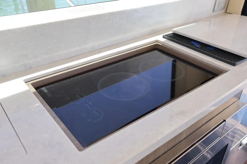 Slide: The Image of Captain's seat in 2021 Regal 42 XO yacht, featuring white upholstery and steering wheel. - 46