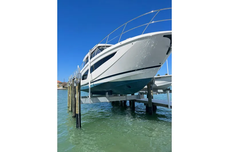 Slide: The Image of 2021 Regal 42 XO yacht elevated on dock over clear blue water. - 6
