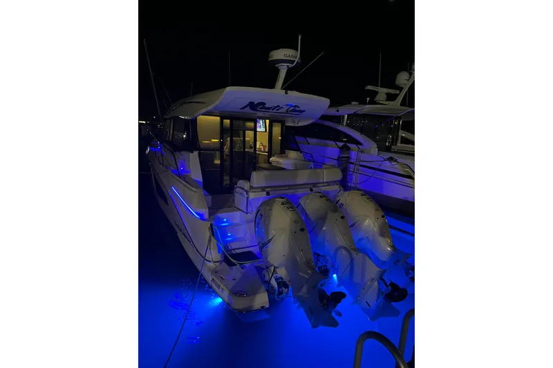 Slide: The Image of 2021 Regal 42 XO yacht illuminated at night with blue underwater lights. - 7