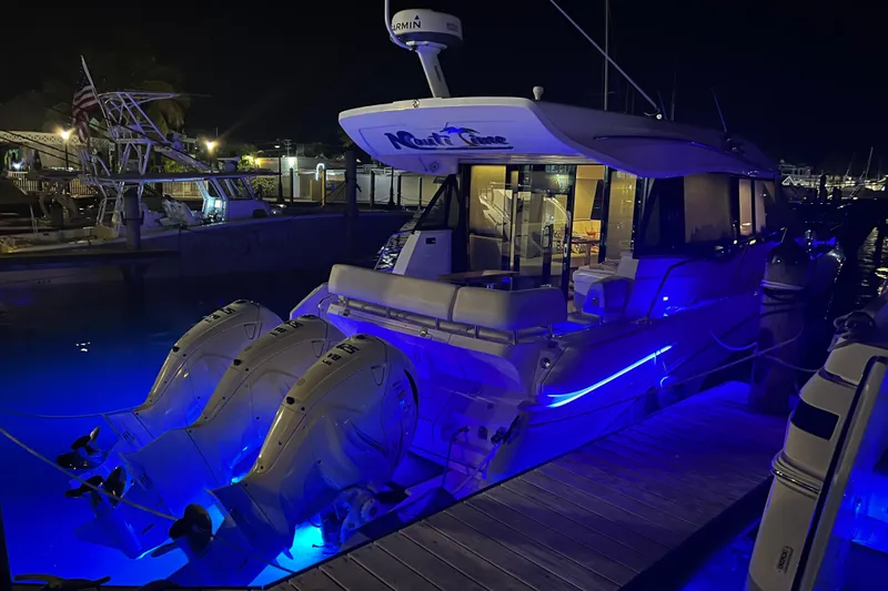 Slide: The Image of 2021 Regal 42 XO yacht docked at night with blue underwater lights. - 9