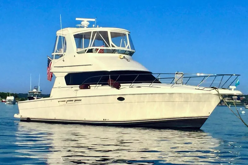 The Image of 2001 Silverton 42 Convertible yacht anchored on calm water under clear blue sky. - 1