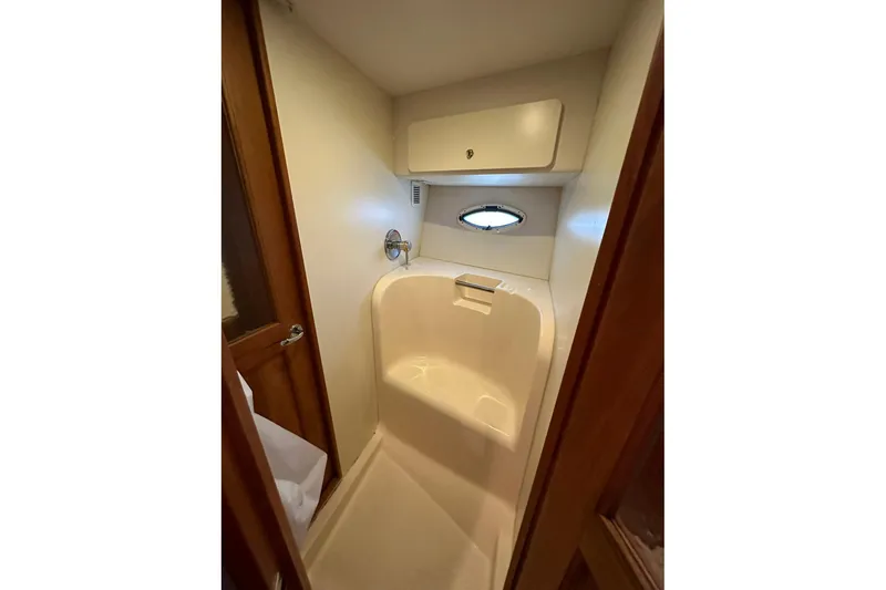 Slide: The Image of Shower area in 2001 Silverton 42 Convertible yacht with wooden door and porthole window. - 10