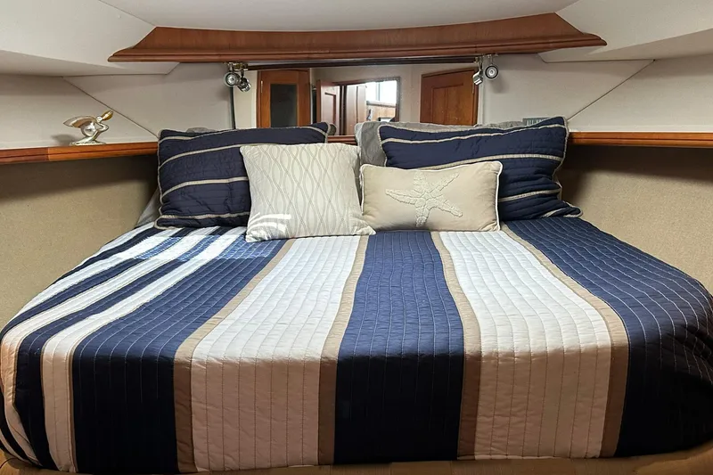 Slide: The Image of Cozy cabin bedroom in a 2001 Silverton 42 Convertible yacht with striped bedding. - 11