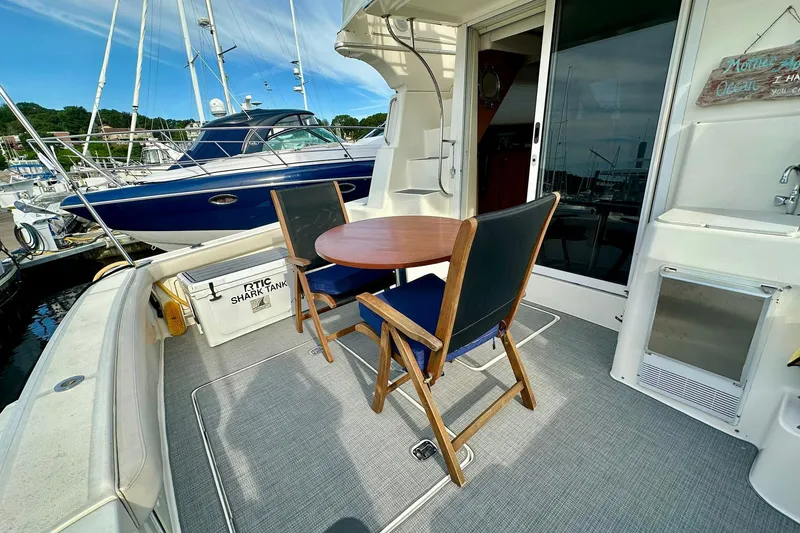 Slide: The Image of 2001 Silverton 42 Convertible yacht deck with chairs and table, docked at marina. - 3