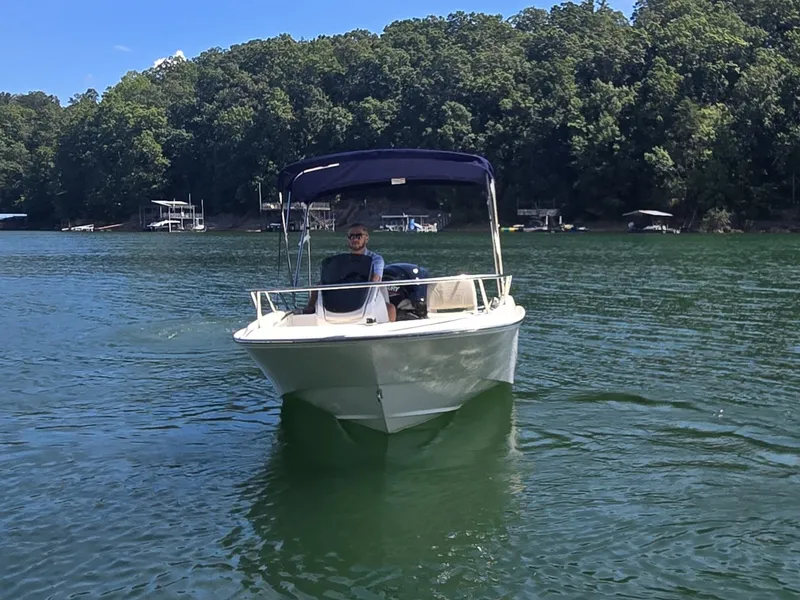 Slide: The Image of A 2026 Boston Whaler 160 Super Sport on a calm lake with a wooded shoreline. - 2