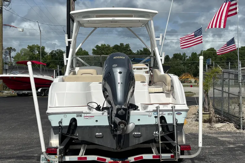 Slide: The Image of 2019 Sea Fox 226 Traveler boat with outboard motor, parked near American flags. - 3