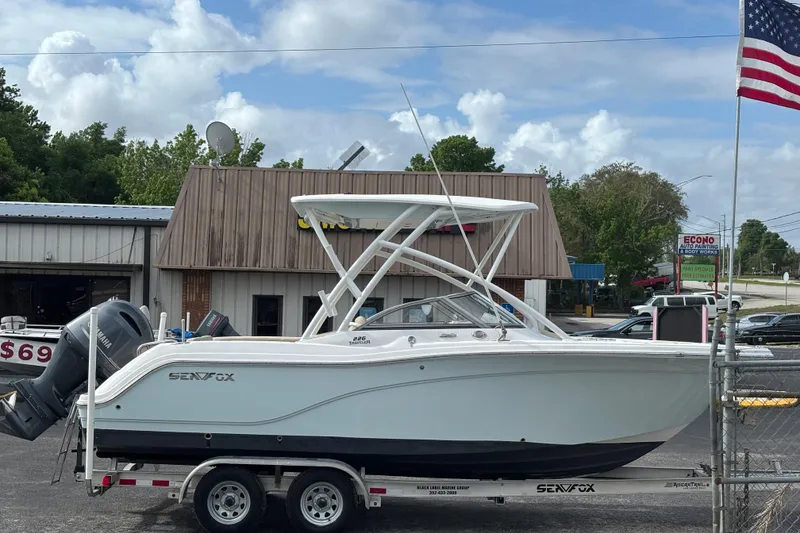 Slide: The Image of 2019 Sea Fox 226 Traveler boat on trailer, parked outside a building with American flag. - 6