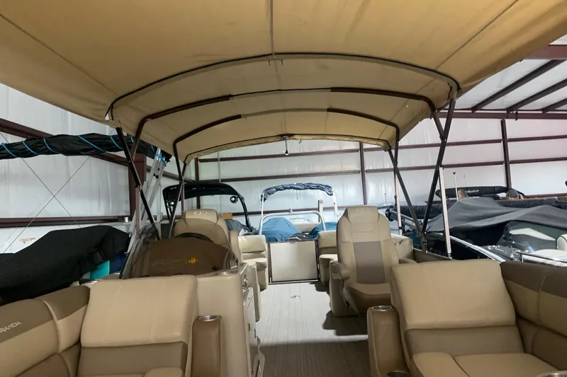 Slide: The Image of 2019 Veranda Relax VR25RC pontoon boat with beige seating and canopy in storage. - 6