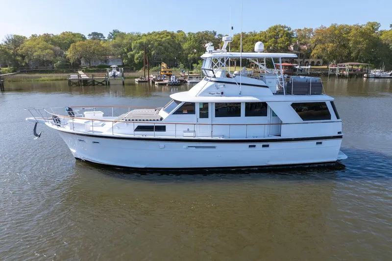 The Image of 1980 Hatteras 53 Motor Yacht cruising on a calm river with scenic background. - 0