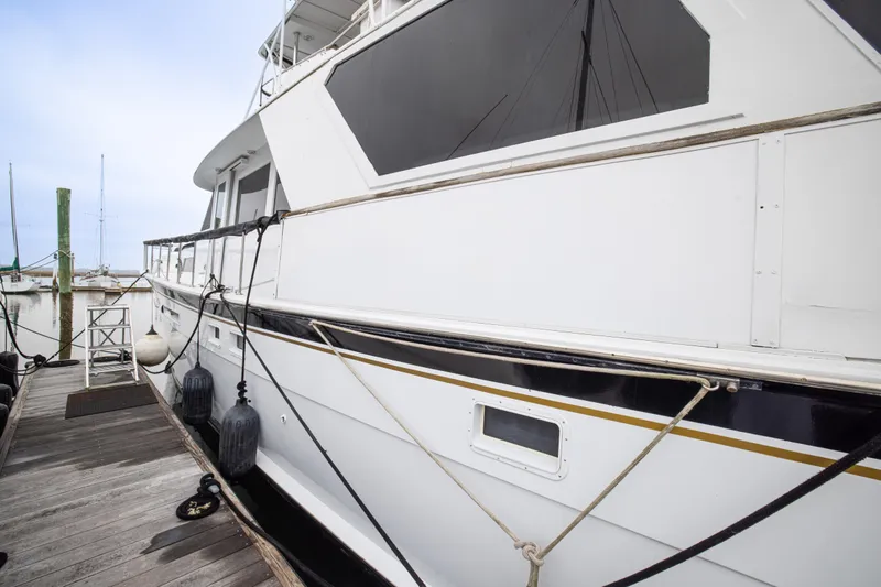 Slide: The Image of 1980 Hatteras 53 Motor Yacht docked, showcasing sleek white exterior and nautical ropes. - 19