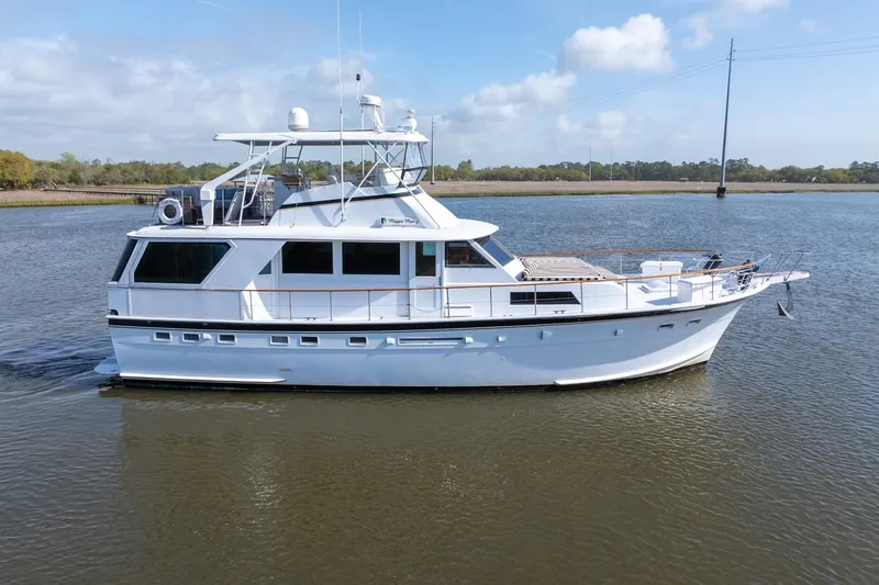 Slide: The Image of 1980 Hatteras 53 Motor Yacht cruising on calm waters under a partly cloudy sky. - 2