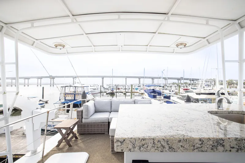 Slide: The Image of 1980 Hatteras 53 Motor Yacht deck with seating, granite countertop, and marina view. - 25