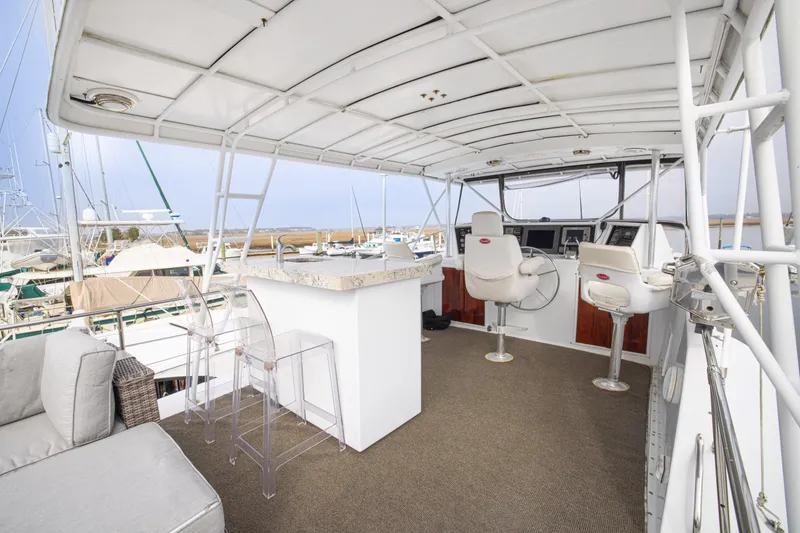 Slide: The Image of 1980 Hatteras 53 Motor Yacht helm with seating, bar area, and marina view. - 32