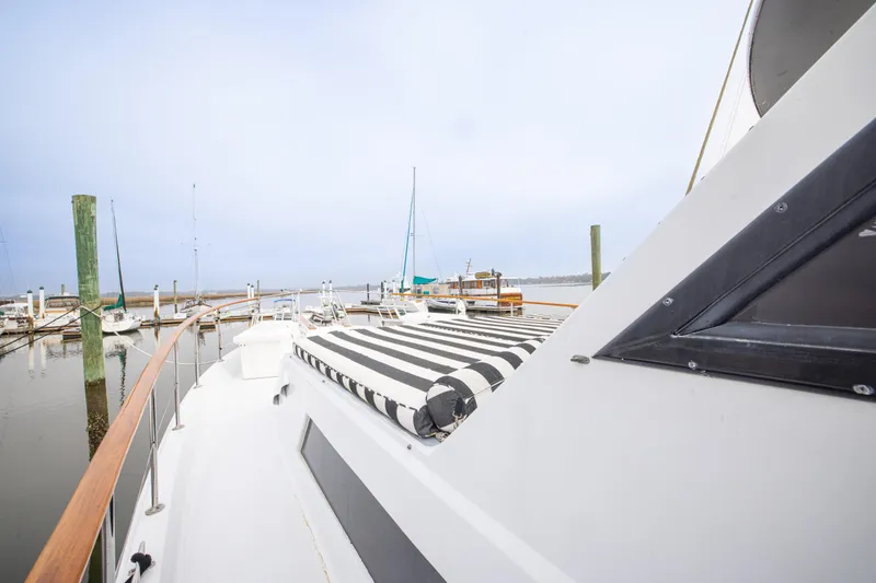 Slide: The Image of 1980 Hatteras 53 Motor Yacht docked, featuring striped deck cover and marina view. - 38