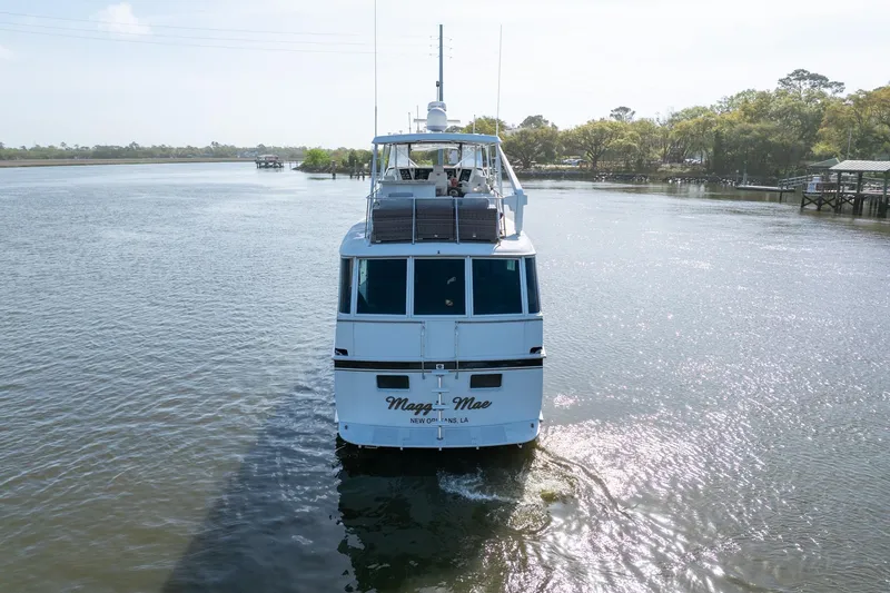 Slide: The Image of 1980 Hatteras 53 Motor Yacht cruising on a serene river under a clear sky. - 4