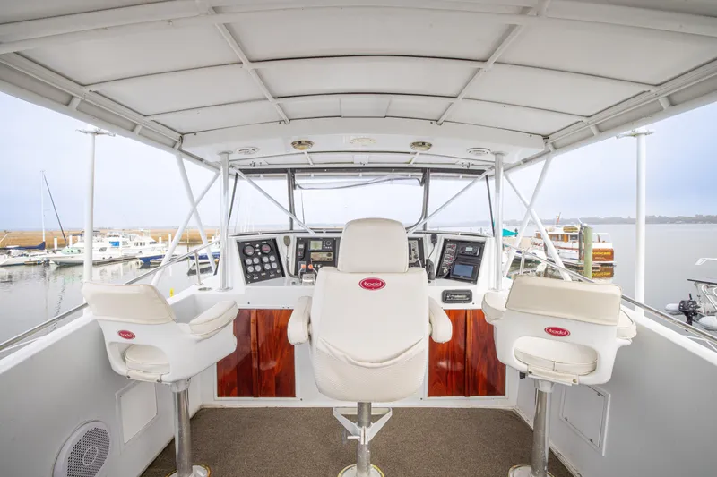 Slide: The Image of 1980 Hatteras 53 Motor Yacht helm with three white captain chairs and control panel. - 57