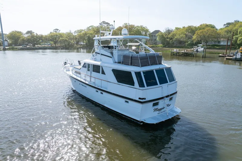 Slide: The Image of 1980 Hatteras 53 Motor Yacht cruising on a calm river with scenic background. - 7