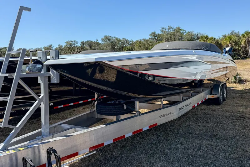 Slide: The Image of 2018 MTI 340X powerboat on trailer, parked on grass under clear blue sky. - 10