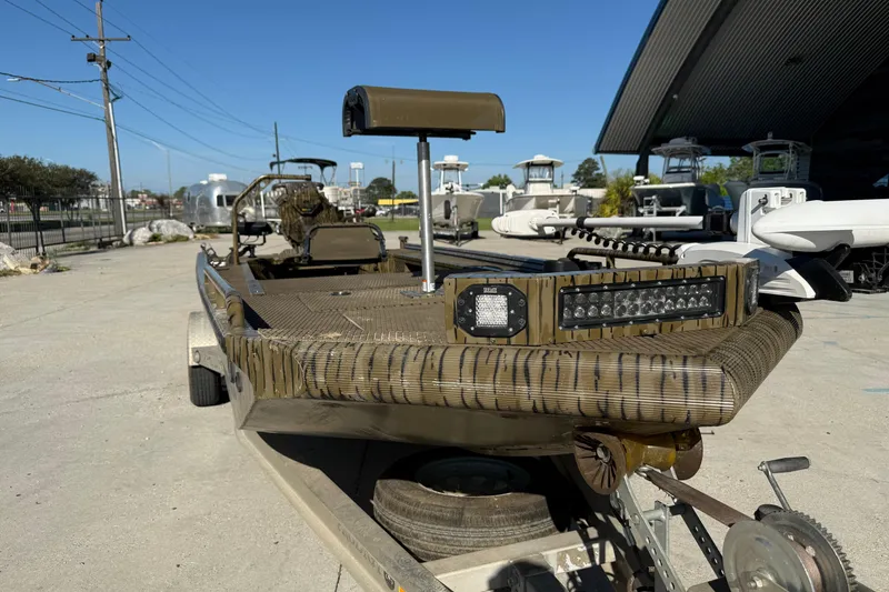 Slide: The Image of 2022 Prodigy 1854 boat with camouflage design, parked on a trailer in a marina. - 10