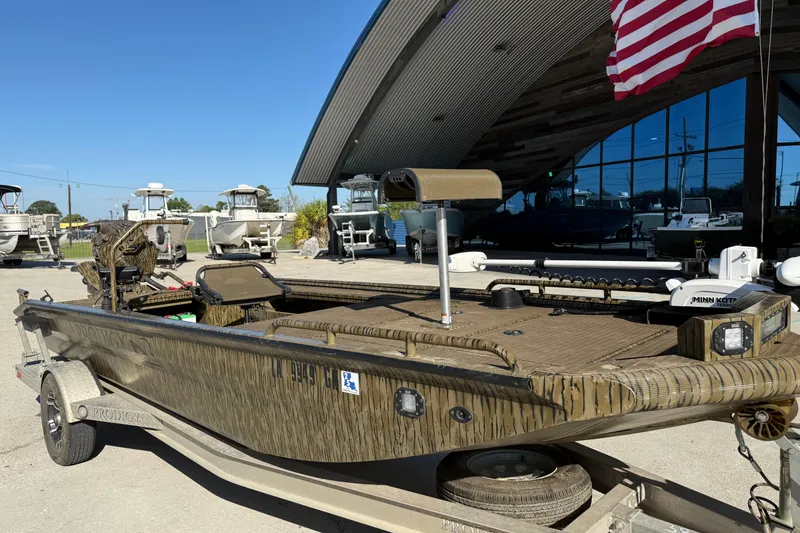 Slide: The Image of 2022 Prodigy 1854 boat on trailer, parked outdoors with American flag in background. - 2