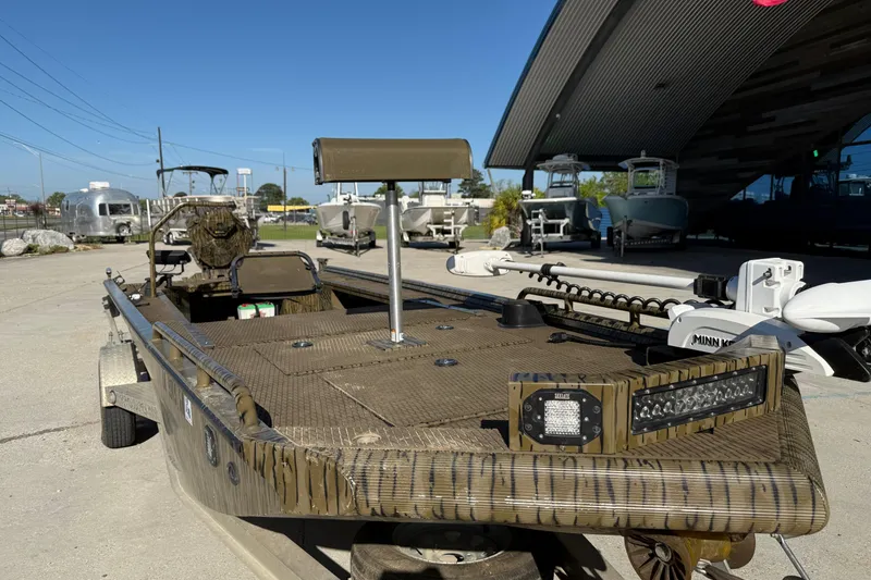 Slide: The Image of 2022 Prodigy 1854 boat with camouflage design, parked outdoors near other boats. - 3