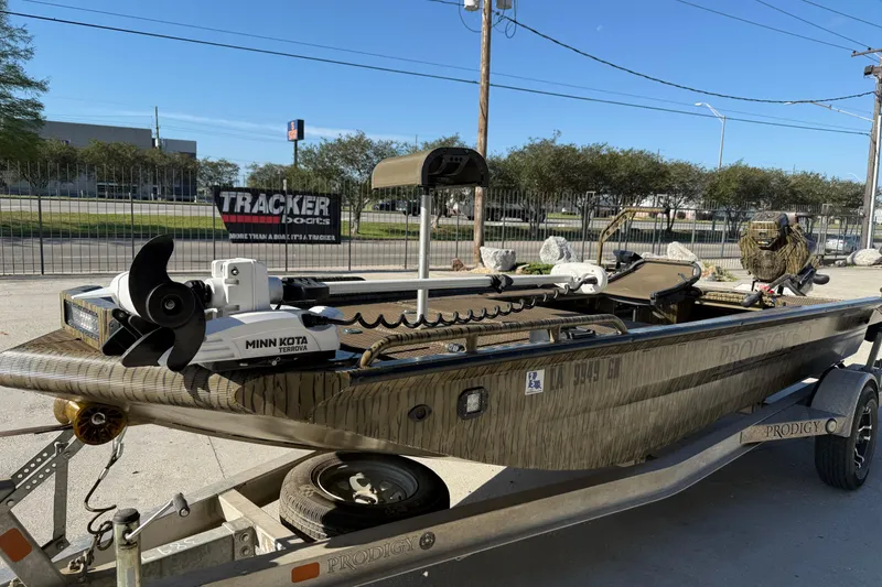 Slide: The Image of 2022 Prodigy 1854 boat with Minn Kota motor on trailer, parked outdoors. - 4