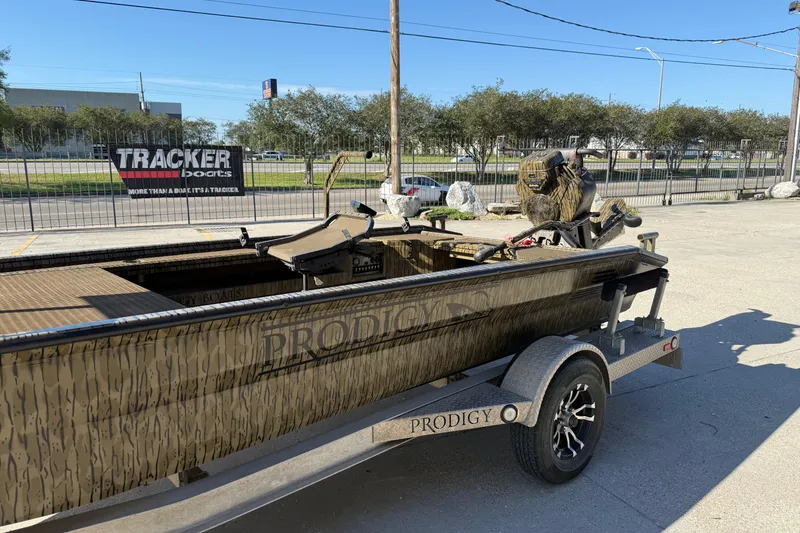 Slide: The Image of 2022 Prodigy 1854 boat on trailer, parked outdoors, with camo design and motor. - 5
